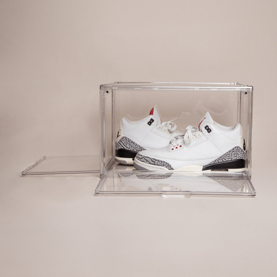 Clear stackable shoe box with both magnetic doors open, holding white and gray Jordan 3 sneakers