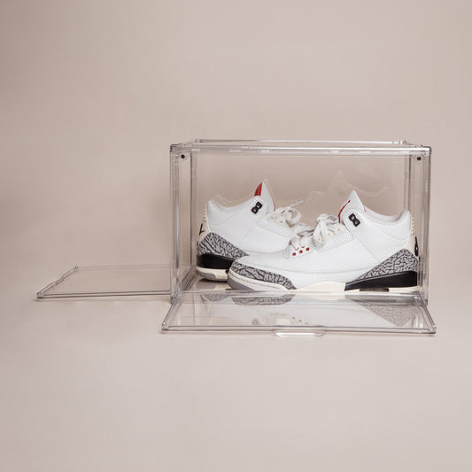 Clear stackable shoe storage box with front and side magnetic doors open, holding white and gray Jordan 3 sneakers