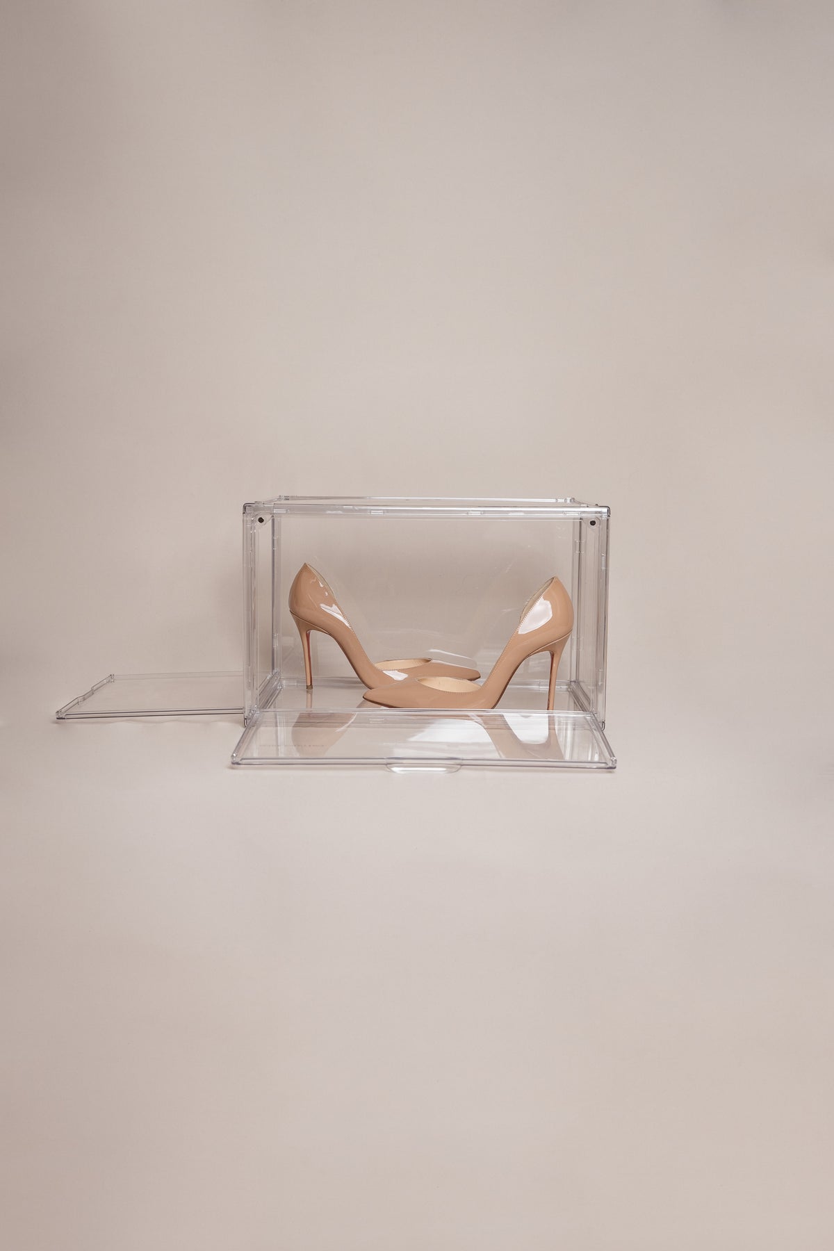 Clear shoe storage box holding a pair of nude heels