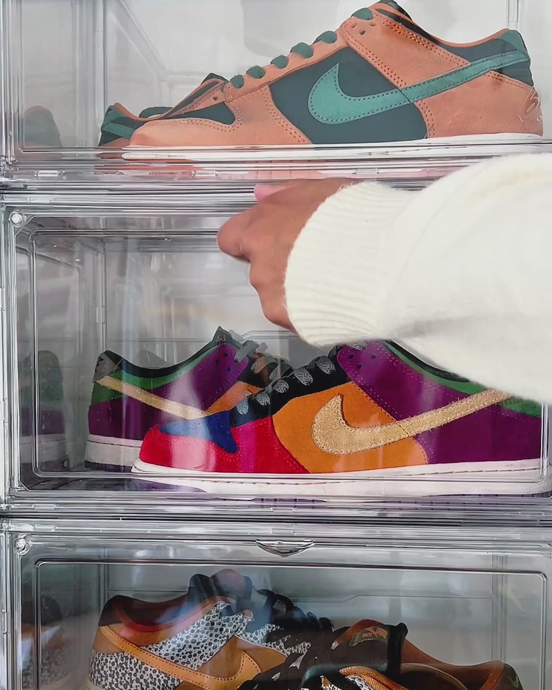 Video of a hand opening the side door of a stacked clear shoe box and taking out a sneaker